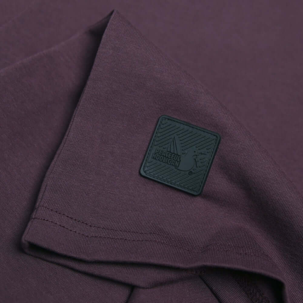 Close-up of the Peaceful Hooligan DUTY T Shirt in grape with black Dove Block badge detail on the sleeve.
