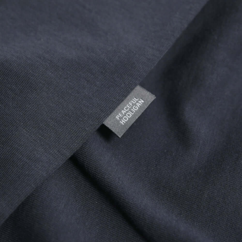 Close-up of the Peaceful Hooligan label on Navy Eric T Shirt fabric.