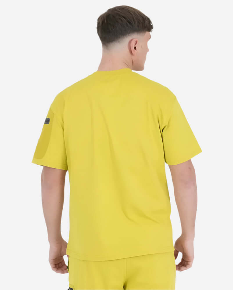 Back view of a man wearing a bright Acid Mustard Peaceful Hooligan FORGE T Shirt, showcasing its vibrant color and casual style.