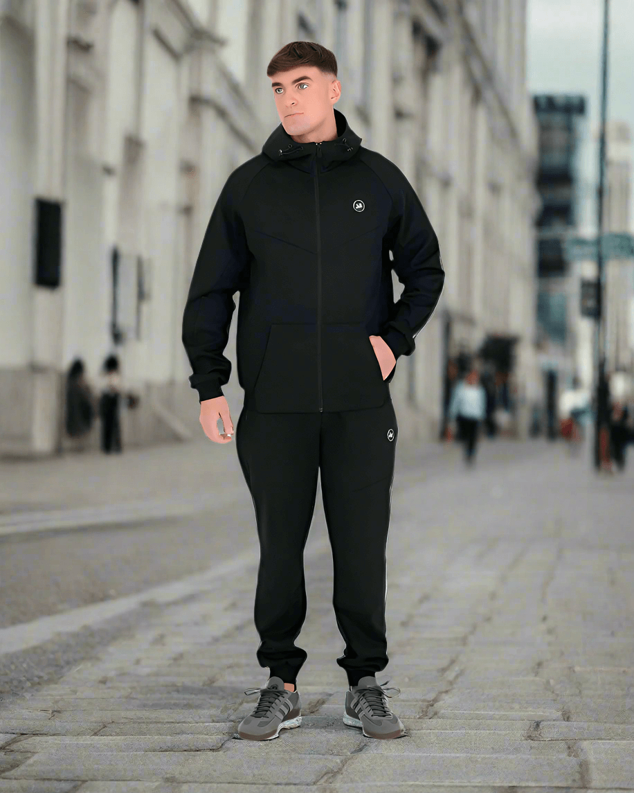 Model wearing the Peaceful Hooligan MADDOX Black Hoodie and matching pants in an urban setting.