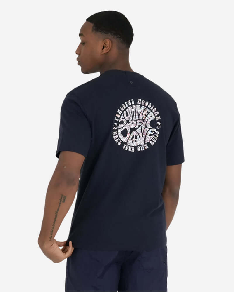 Man wearing navy Peaceful Hooligan SUMMER OF DOVE T-shirt showcasing back logo design.