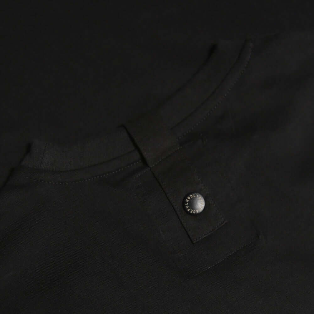 Close-up view of the collar and PH sports snap detail on the black Peaceful Hooligan TEAR US APART T-shirt.