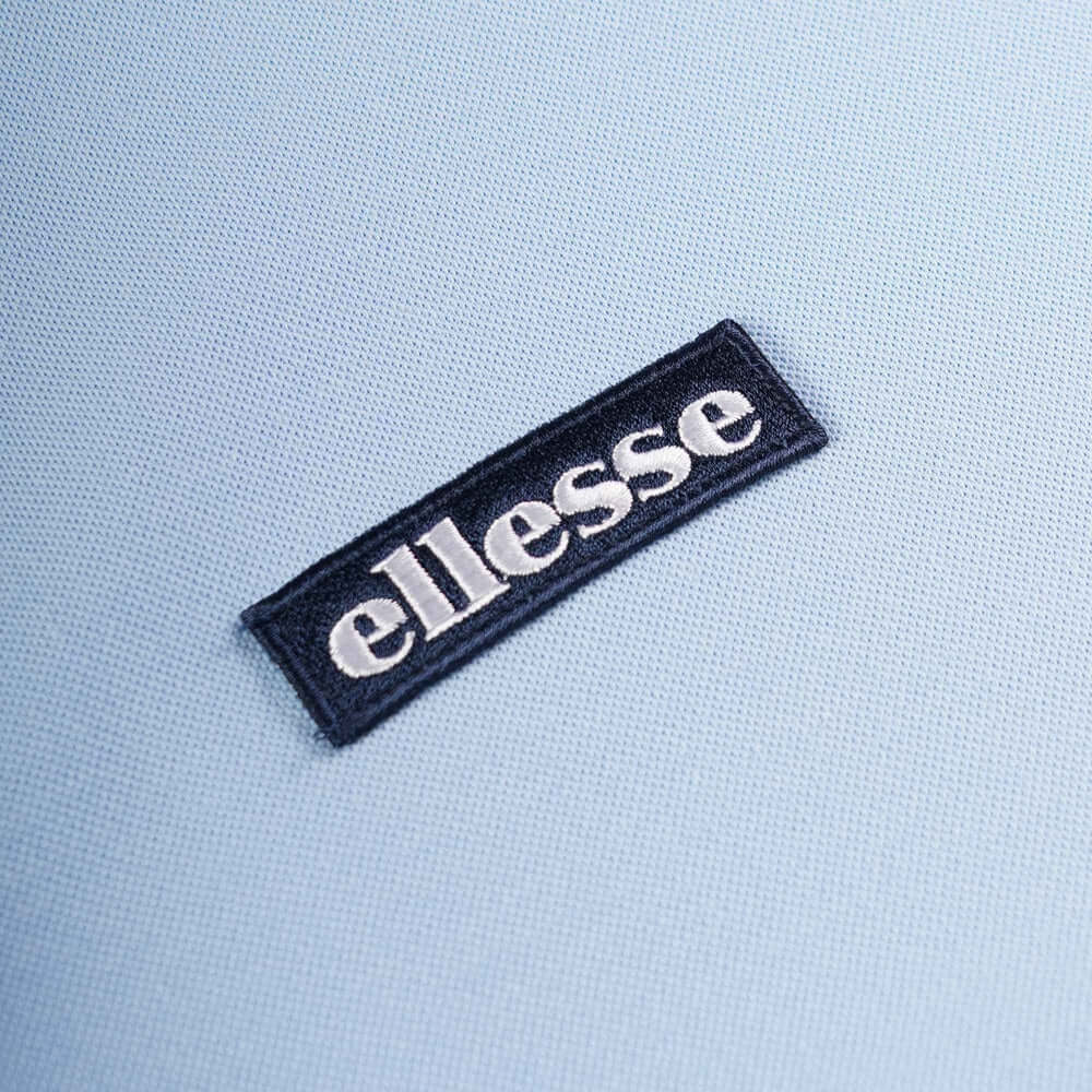 Close-up of the Ellesse logo on a light blue BELVIDER T-Shirt from the Live Forever Collection.