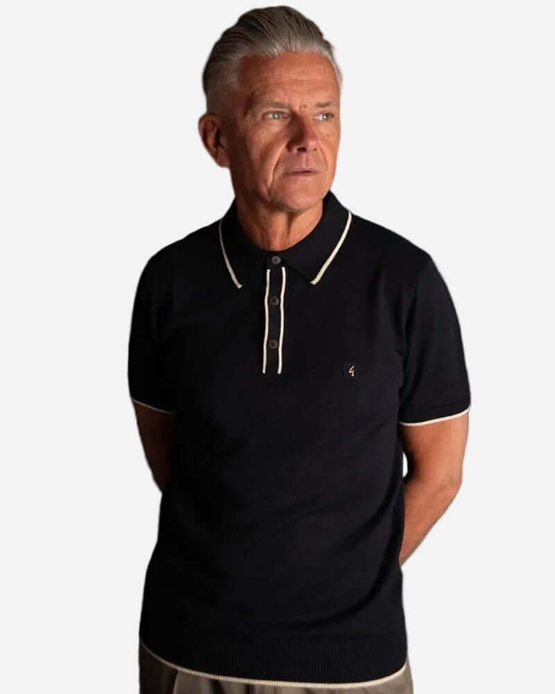 Gabicci LINEKER Short Sleeve Polo Black worn by a model, showcasing its vintage sportswear style and contrast tipping.