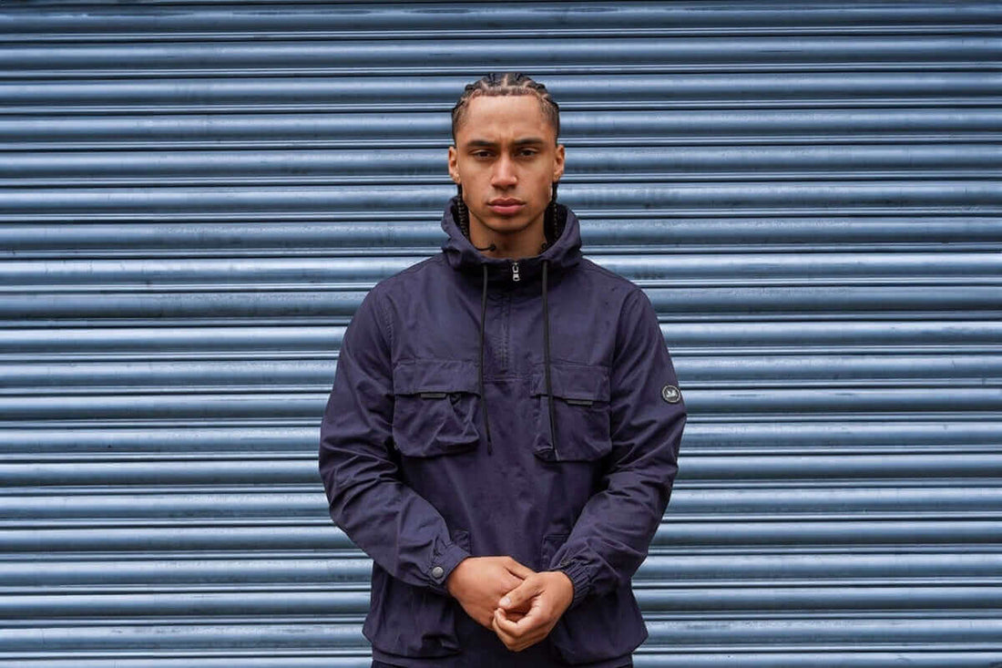 Model wearing a Peaceful Hooligan jacket in front of a textured blue background, showcasing men's casuals clothing.