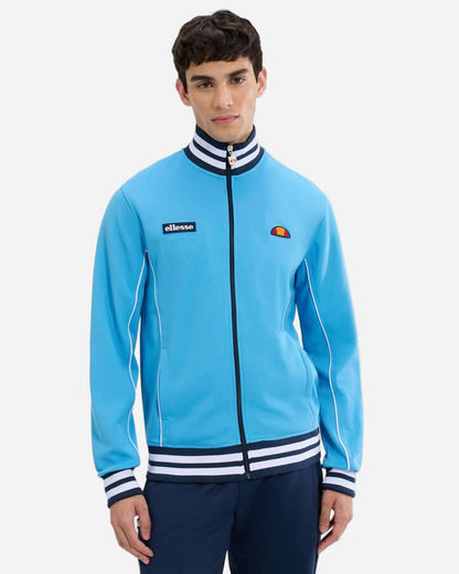 Ellesse MILAN Track Jacket Blue/Navy worn by a model, featuring a blue tricot design with navy accents and retro stripes.