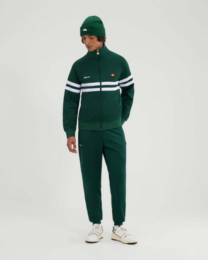 Ellesse RIMINI Track Jacket Dark Green worn by a model, showcasing street style with a funnel neck and bold branding.