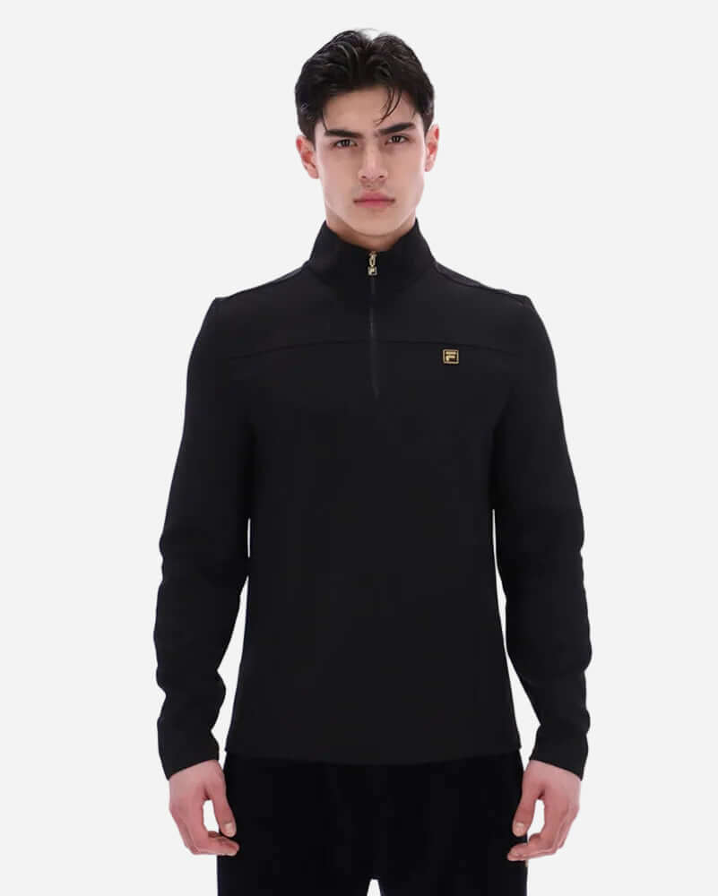 Fila Gold HOGAN Quarter Zip Top Black on a model, featuring a quarter zip design and ribbed cuffs for a modern look.