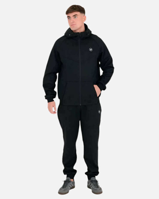 Man wearing the black Peaceful Hooligan MADDOX Hoodie and matching pants, showcasing streetwear style.