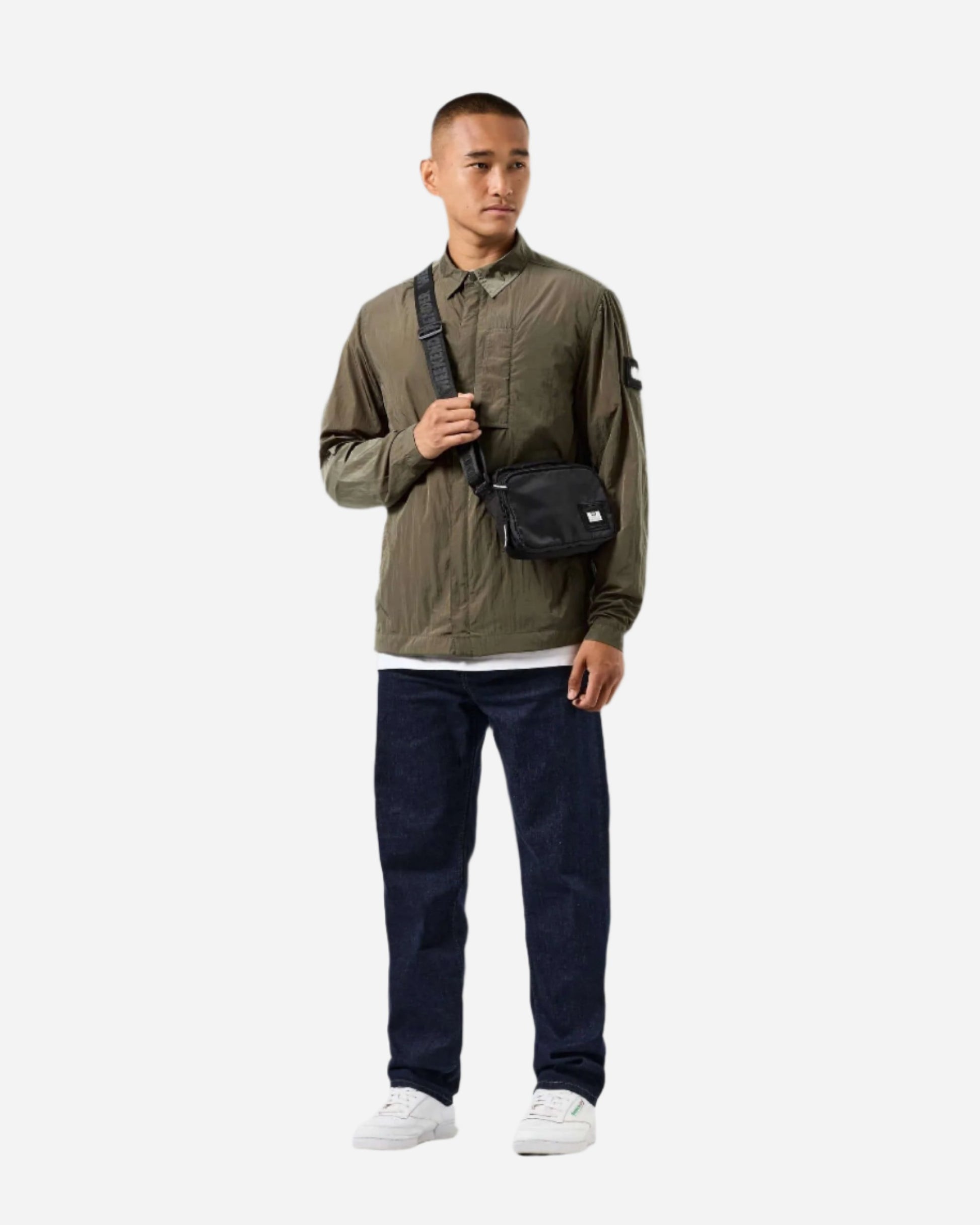 Man wearing Weekend Offender PORTER Overshirt in Castle Green for outdoor activities, paired with dark jeans and white sneakers