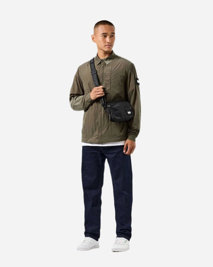 Man wearing Weekend Offender PORTER Overshirt in Castle Green for outdoor activities, paired with dark jeans and white sneakers